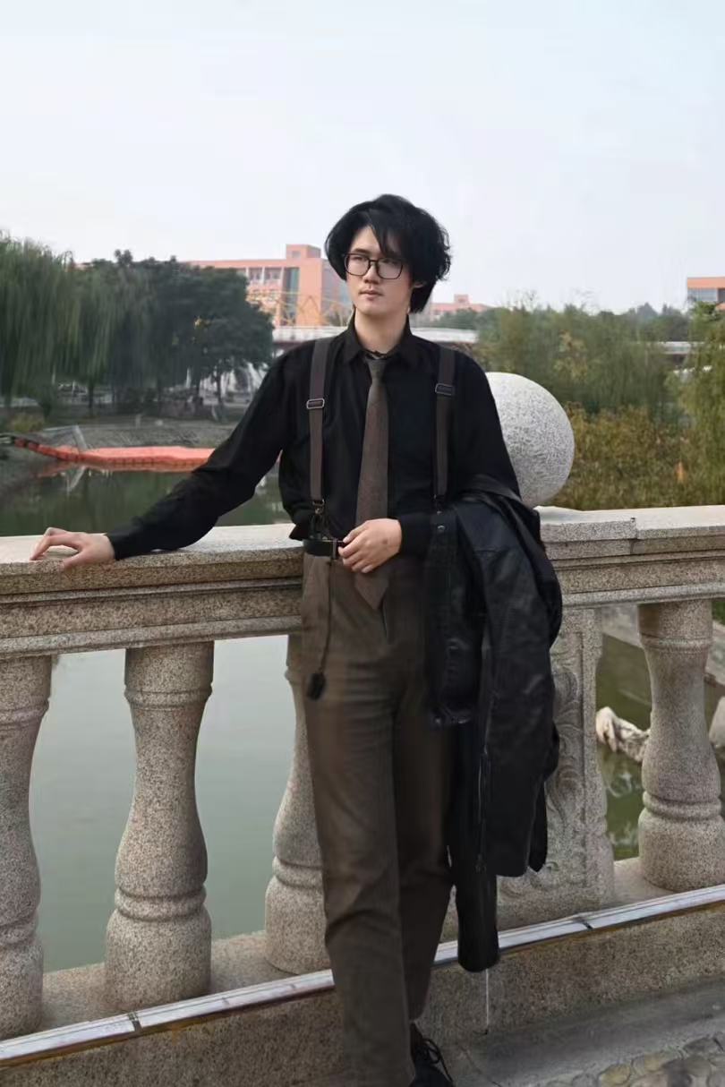 虫二（祝赫）本人照片，站在河边石栏旁。